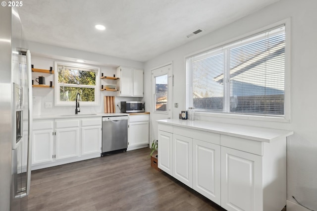 kitchen with appliances with stainless steel finishes, sink, dark wood-type flooring, and white cabinets