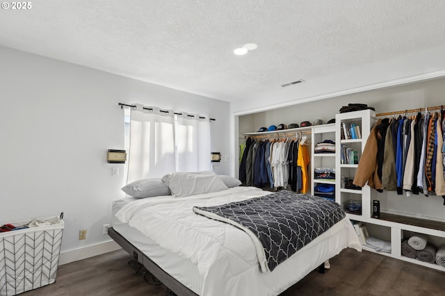 bedroom featuring dark wood-type flooring, a closet, and a textured ceiling