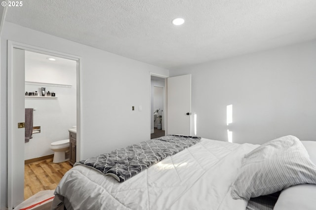 bedroom with connected bathroom, hardwood / wood-style flooring, and a textured ceiling