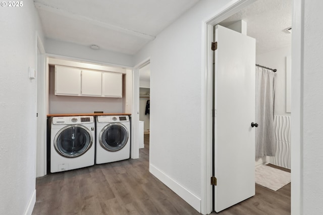 laundry room with cabinets, washing machine and clothes dryer, and light hardwood / wood-style flooring