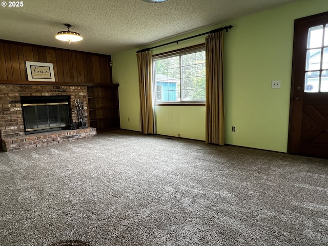 1011 Heather Ct, Reedsport, OR 97467 - unfurnished living room featuring healthy amount of natural light, carpet floors, a brick fireplace, a textured ceiling, and wooden walls