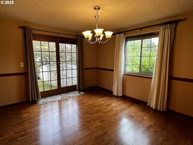 1011 Heather Ct, Reedsport, OR 97467 - empty room featuring a chandelier, a textured ceiling, dark wood-type flooring, and healthy amount of natural light