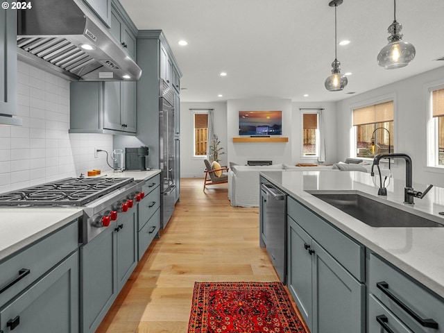 kitchen with sink, gray cabinets, appliances with stainless steel finishes, hanging light fixtures, and extractor fan