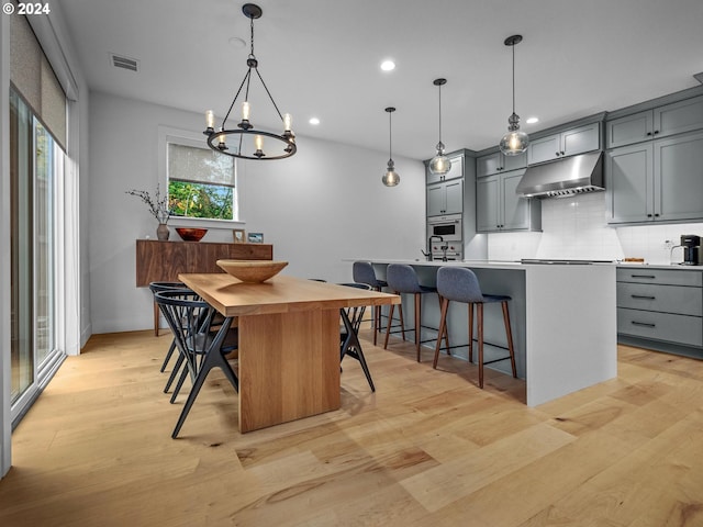 kitchen featuring pendant lighting, gray cabinetry, and an island with sink