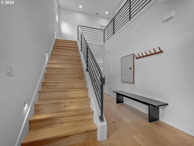 stairs featuring a towering ceiling and wood-type flooring