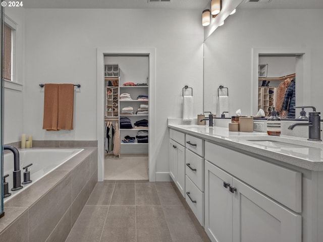 bathroom featuring vanity, tile patterned floors, and tiled bath