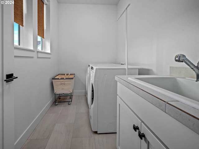 clothes washing area featuring separate washer and dryer, sink, and cabinets