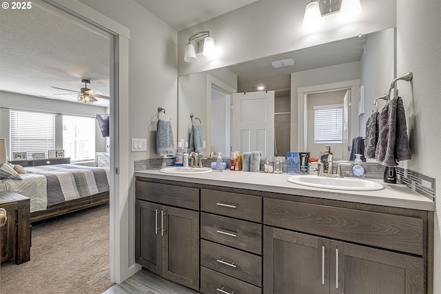 bathroom with ceiling fan, a textured ceiling, and vanity