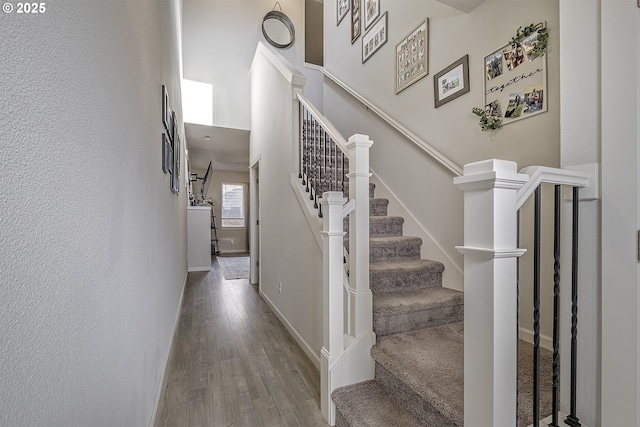 stairway featuring a towering ceiling and hardwood / wood-style floors