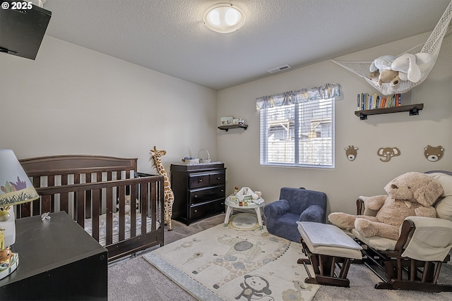 bedroom with a textured ceiling, light carpet, and a crib