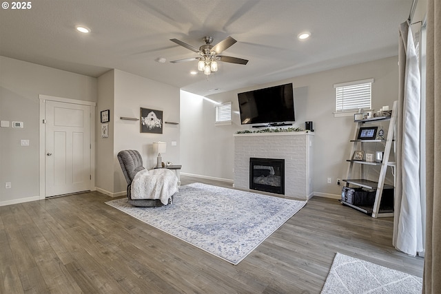 living room with ceiling fan, a fireplace, and hardwood / wood-style flooring