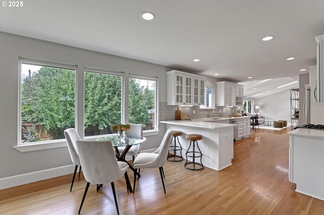 dining area featuring light hardwood / wood-style floors, sink, and a textured ceiling