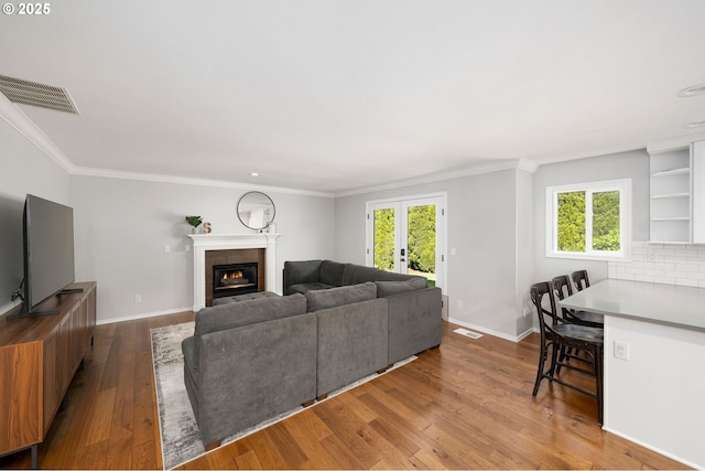 17890 SW 109th Ave, Tualatin, OR 97062 - living area with hardwood / wood-style floors, a tiled fireplace, ornamental molding, baseboards, and healthy amount of natural light