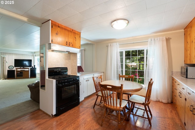 77690 Brock Rd, Oakridge, OR 97463 - kitchen featuring black range with gas stovetop, stainless steel microwave, under cabinet range hood, light countertops, and crown molding