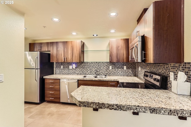 kitchen featuring sink, light tile patterned floors, backsplash, stainless steel appliances, and kitchen peninsula