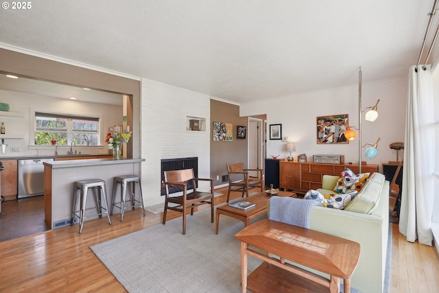living room with a fireplace, light wood-type flooring, and crown molding