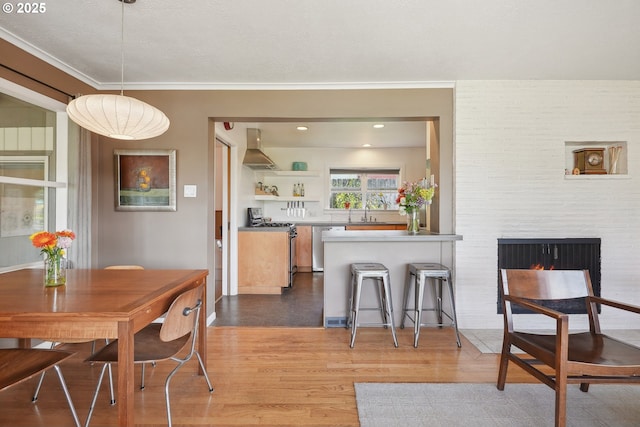 dining space featuring wood finished floors, a large fireplace, and ornamental molding
