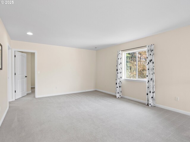 empty room featuring recessed lighting, light colored carpet, and baseboards