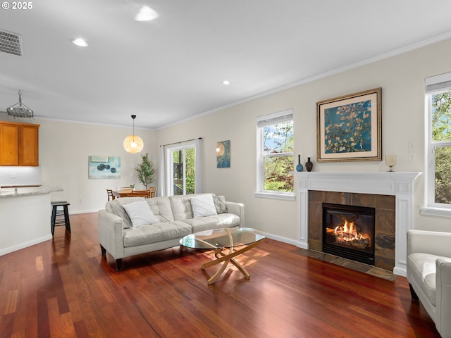 living room featuring a wealth of natural light, dark wood-type flooring, visible vents, and a tile fireplace
