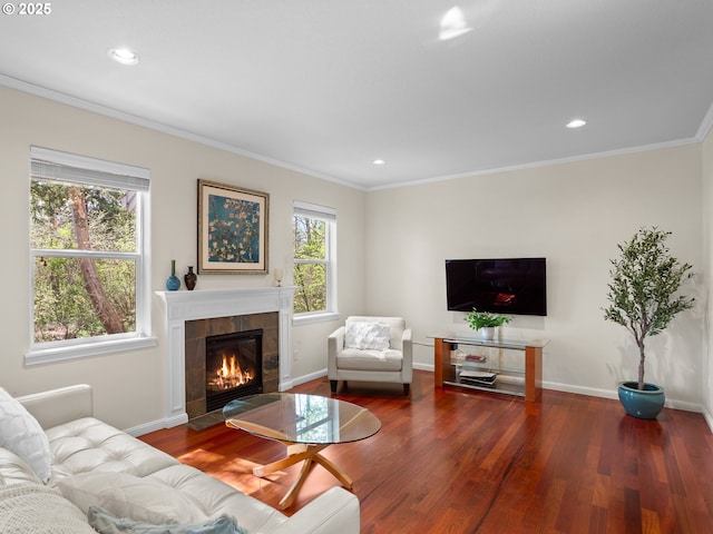 living area featuring a tile fireplace, wood finished floors, baseboards, and ornamental molding