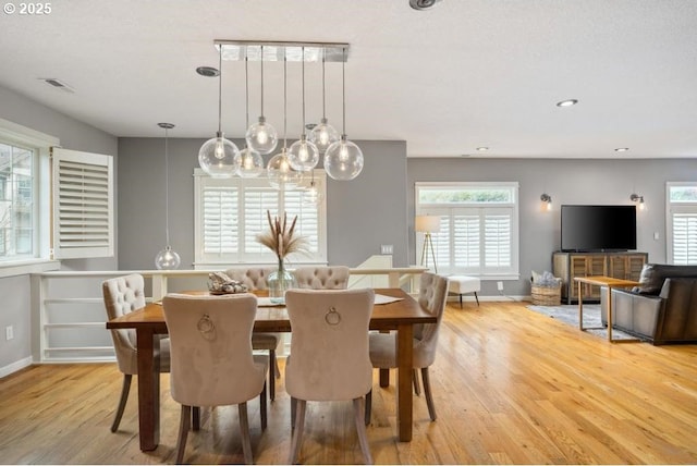 dining room with plenty of natural light, light wood finished floors, baseboards, recessed lighting, and a chandelier