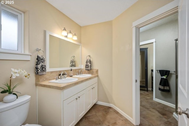 bathroom with double vanity, toilet, decorative backsplash, baseboards, and tile patterned floors