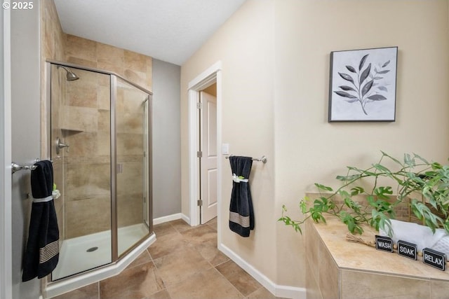 full bathroom with a shower stall and baseboards