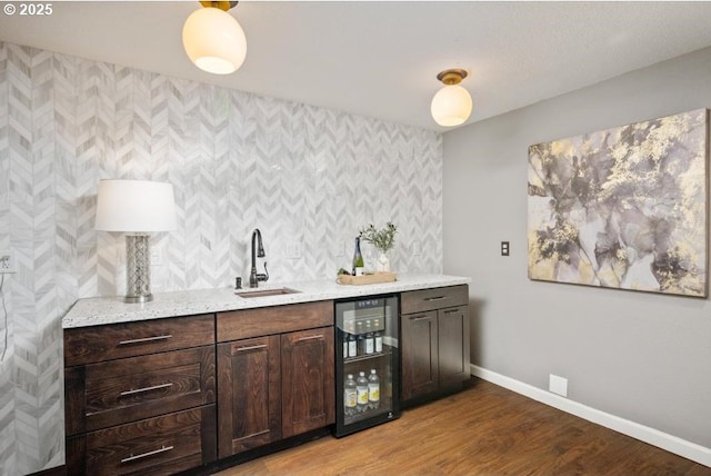 indoor wet bar featuring beverage cooler, baseboards, and light wood-style floors