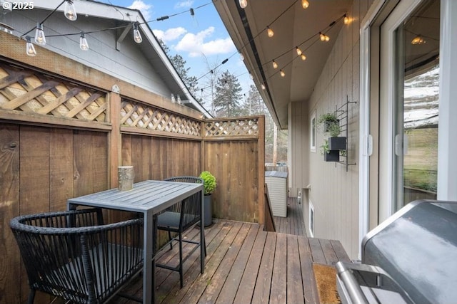 wooden terrace with outdoor dining area and grilling area