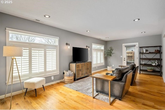 living area with recessed lighting, visible vents, baseboards, and wood finished floors