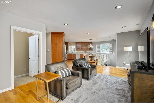 living area featuring light wood-type flooring, baseboards, recessed lighting, and a chandelier