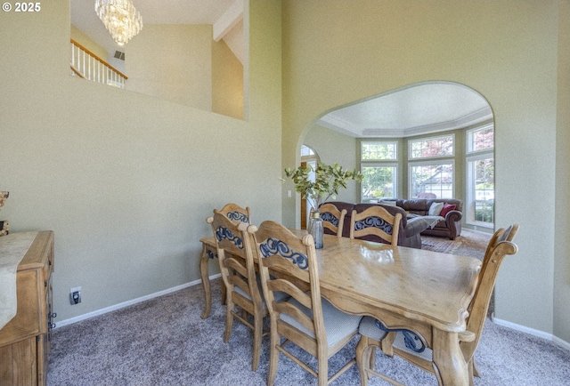 carpeted dining space featuring baseboards, a chandelier, arched walkways, and lofted ceiling