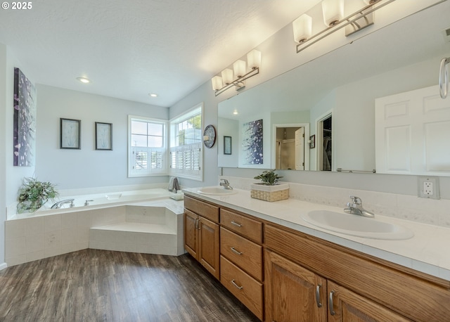 full bath featuring a bath, double vanity, wood finished floors, an enclosed shower, and recessed lighting