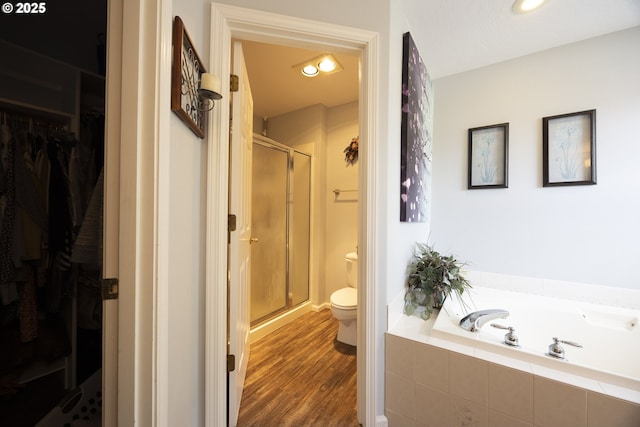 full bathroom featuring toilet, a shower stall, wood finished floors, and a bath