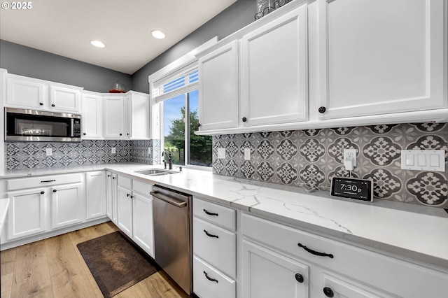 kitchen featuring a sink, white cabinets, light wood-style floors, and stainless steel appliances