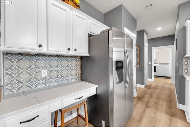 kitchen with light wood-style floors, decorative backsplash, baseboards, stainless steel fridge, and white cabinetry
