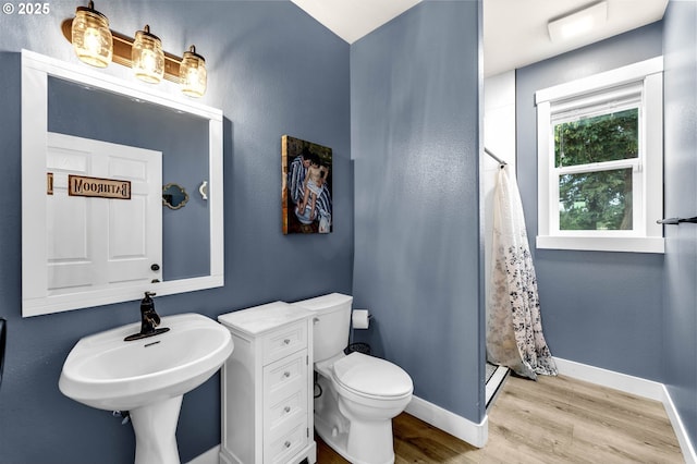 bathroom with baseboards, a stall shower, toilet, and wood finished floors