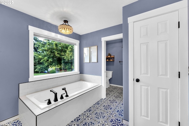 full bathroom featuring a garden tub, baseboards, toilet, and an inviting chandelier