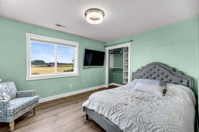 bedroom with visible vents, baseboards, wood finished floors, and a closet