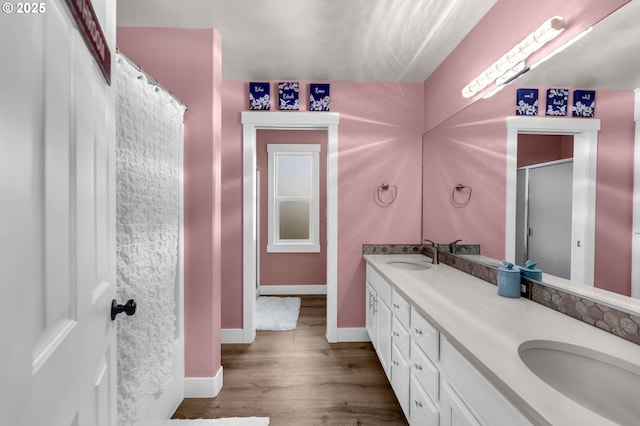 bathroom featuring double vanity, a sink, baseboards, and wood finished floors