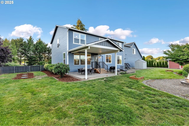 rear view of property with fence, a shed, an outbuilding, a patio, and a yard