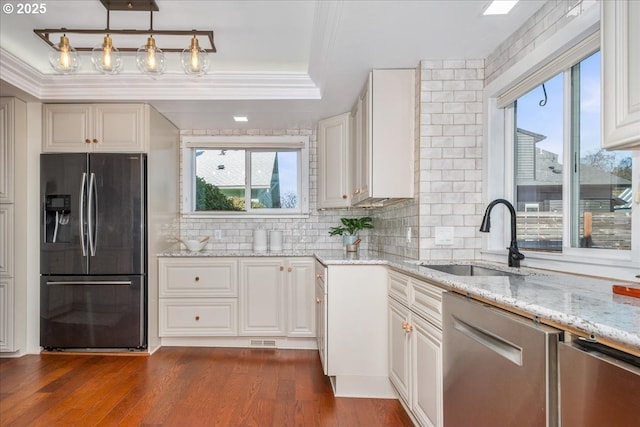 kitchen featuring a sink, light stone counters, appliances with stainless steel finishes, a raised ceiling, and dark wood-style flooring