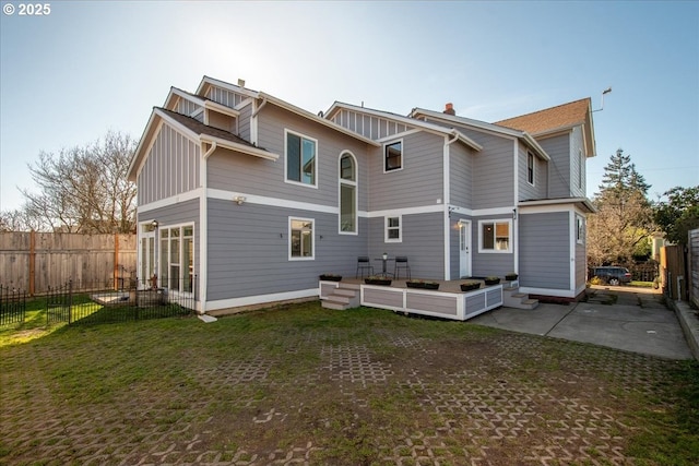 rear view of house with a yard, a patio, board and batten siding, and fence