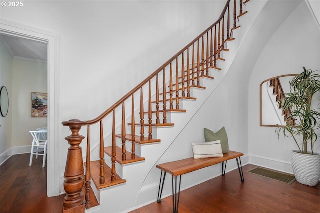 stairway featuring visible vents, baseboards, and wood finished floors