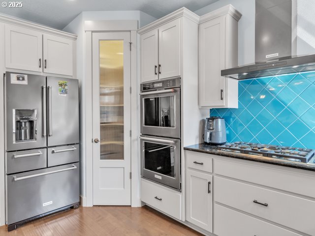 14509 SE Faircrest St, Clackamas, OR 97015 - kitchen with appliances with stainless steel finishes, wall chimney range hood, light wood-style floors, and white cabinets