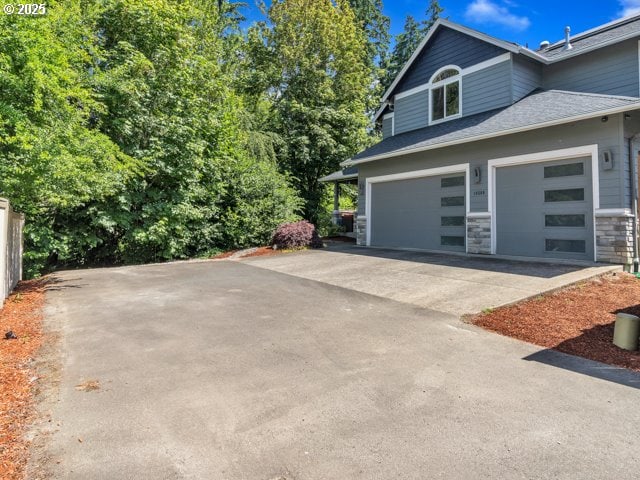 14509 SE Faircrest St, Clackamas, OR 97015 - view of home's exterior with concrete driveway, stone siding, a shingled roof, and an attached garage
