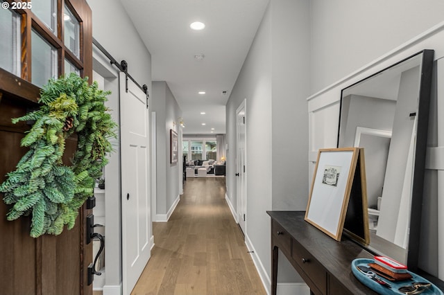 hallway with light hardwood / wood-style floors and a barn door