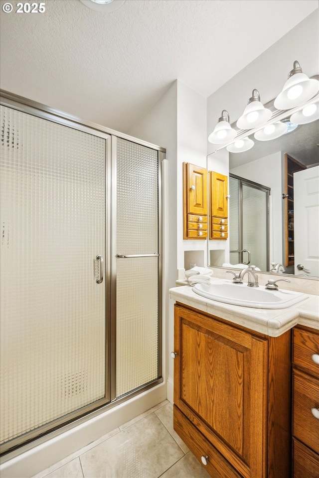 bathroom featuring a shower with shower door, a textured ceiling, tile patterned floors, and vanity