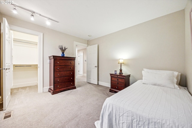 carpeted bedroom featuring a spacious closet, a closet, and rail lighting