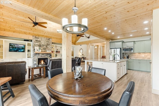 dining space featuring lofted ceiling, sink, wood ceiling, a fireplace, and light hardwood / wood-style floors